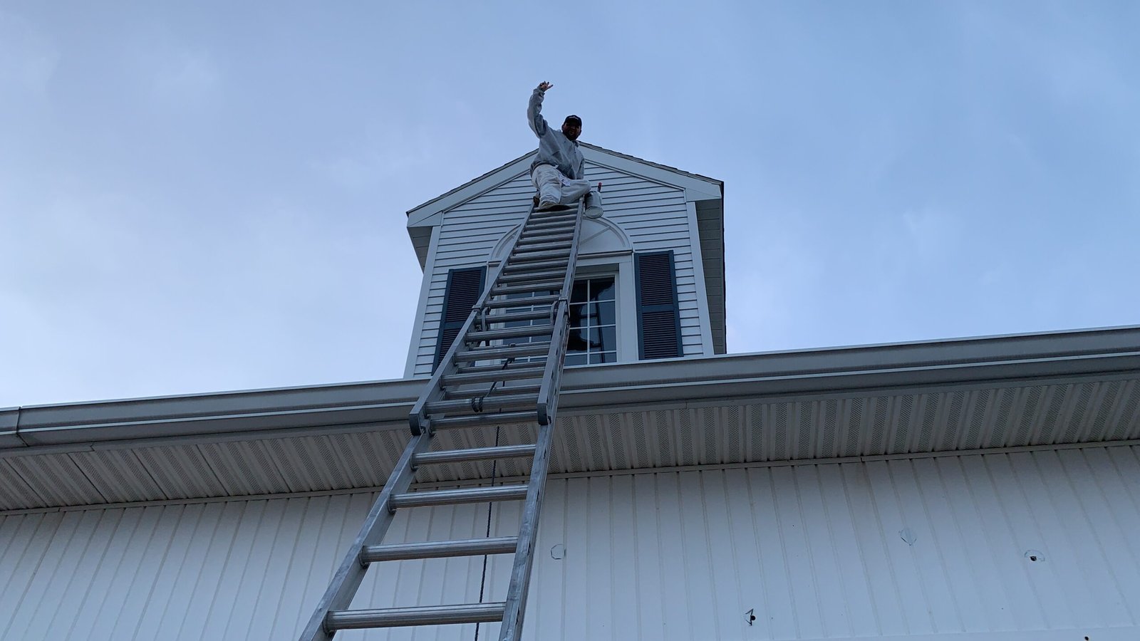 Exterior painting at roof height on a Cape Cod building by Fabricio Painting